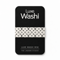 A black rectangular card or mini package with rounded corners, featuring the text 'Luxe Washi' at the top and 'Luxe Washi Mini' at the bottom, plus 'THE JADORE STUDIO.' A horizontal band across the center shows a repeating black monogram pattern on an off-white background.
